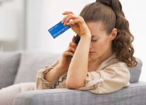 Frustrated young woman with credit card and talking phone